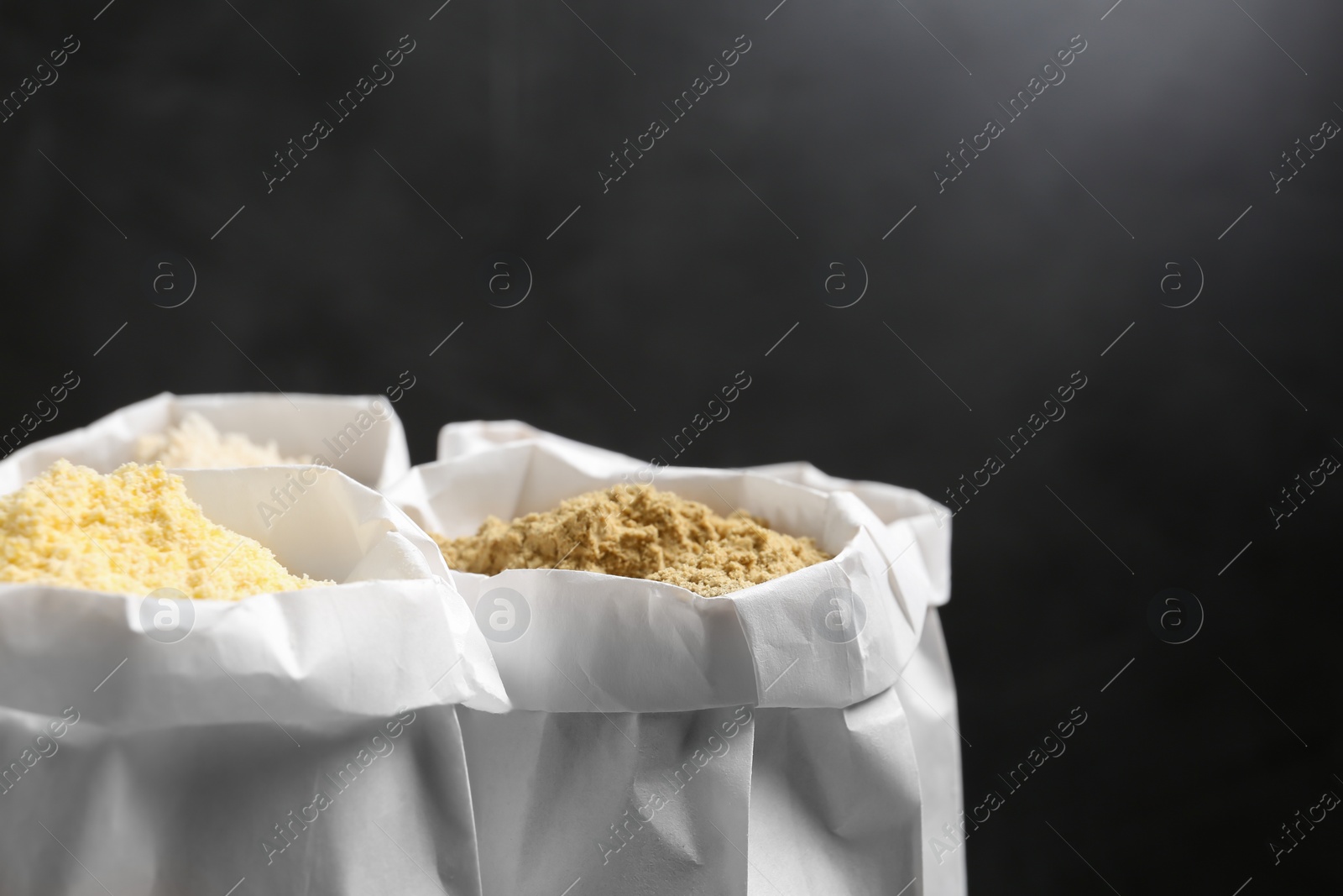 Photo of Paper bags with different types of flour on dark background. Space for text