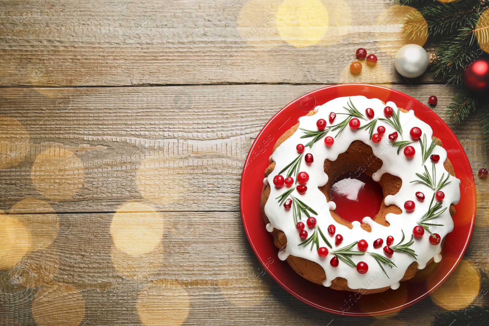 Image of Flat lay composition with traditional Christmas cake and decorations on wooden table, space for text. Bokeh effect