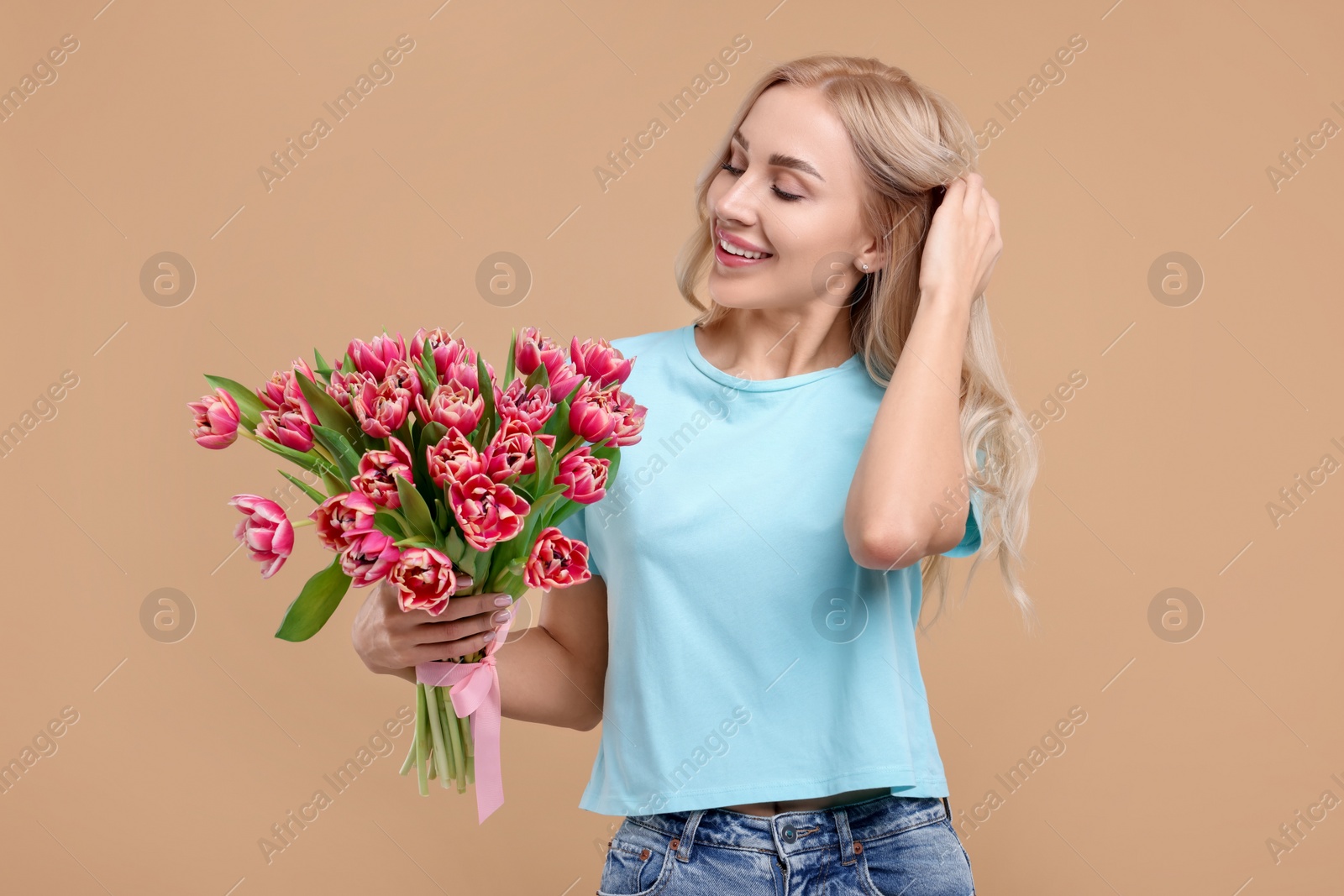 Photo of Happy young woman with beautiful bouquet on beige background