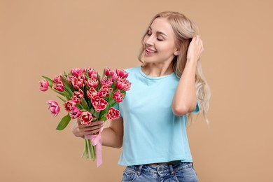 Happy young woman with beautiful bouquet on beige background