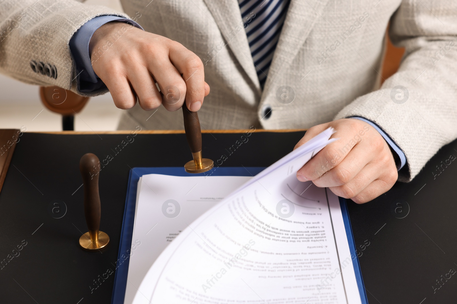 Photo of Notary stamping document at table, closeup view