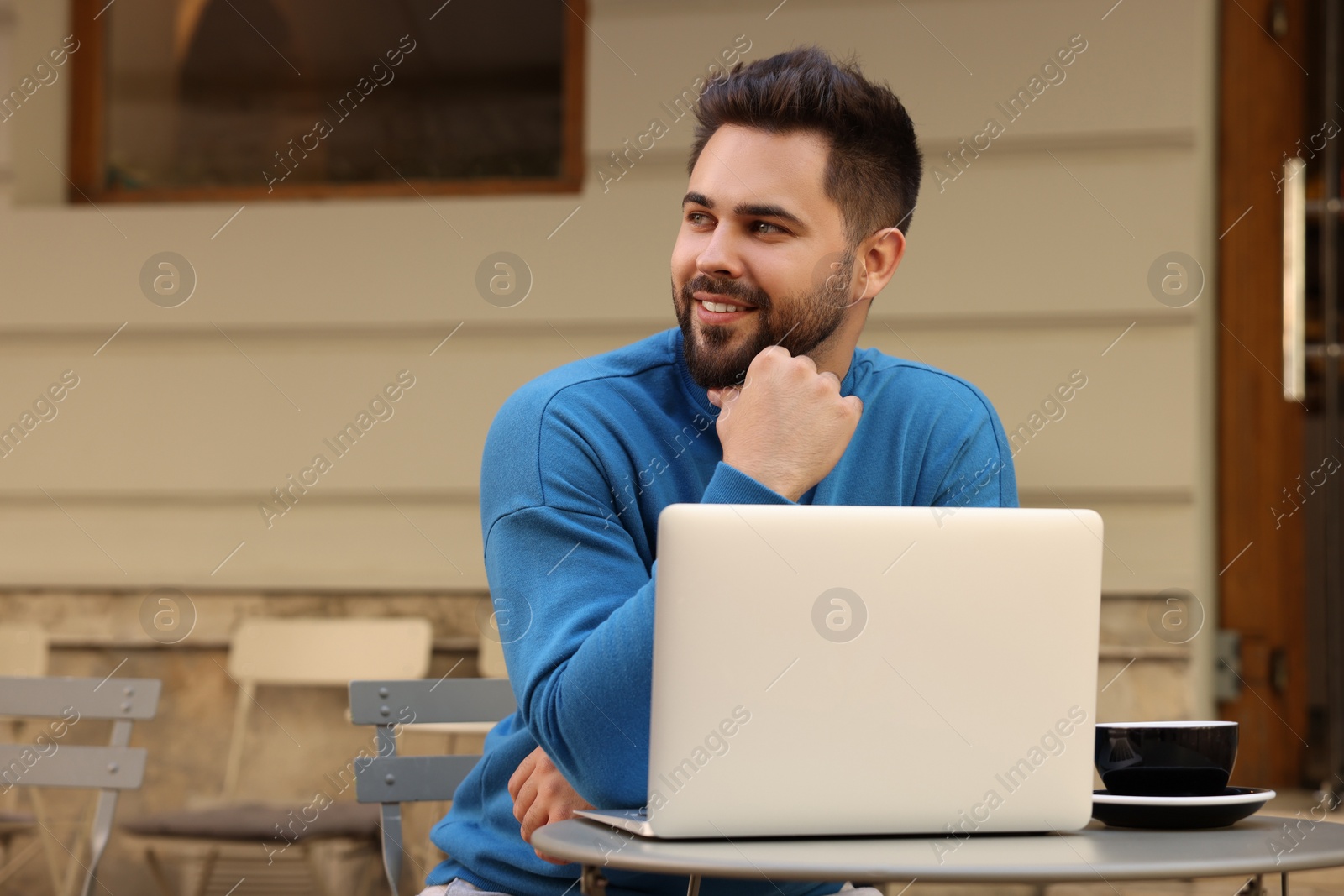 Photo of Handsome young man with laptop at table in outdoor cafe