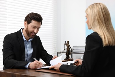 Man signing document at table in lawyer's office