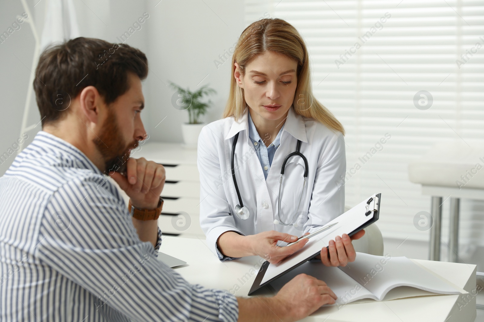 Photo of Doctor consulting patient at white table in clinic