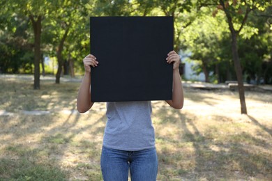 Woman holding blank poster outdoors. Mockup for design