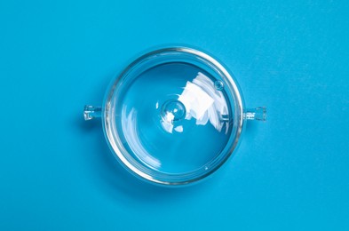Glass pot with lid on light blue background, top view