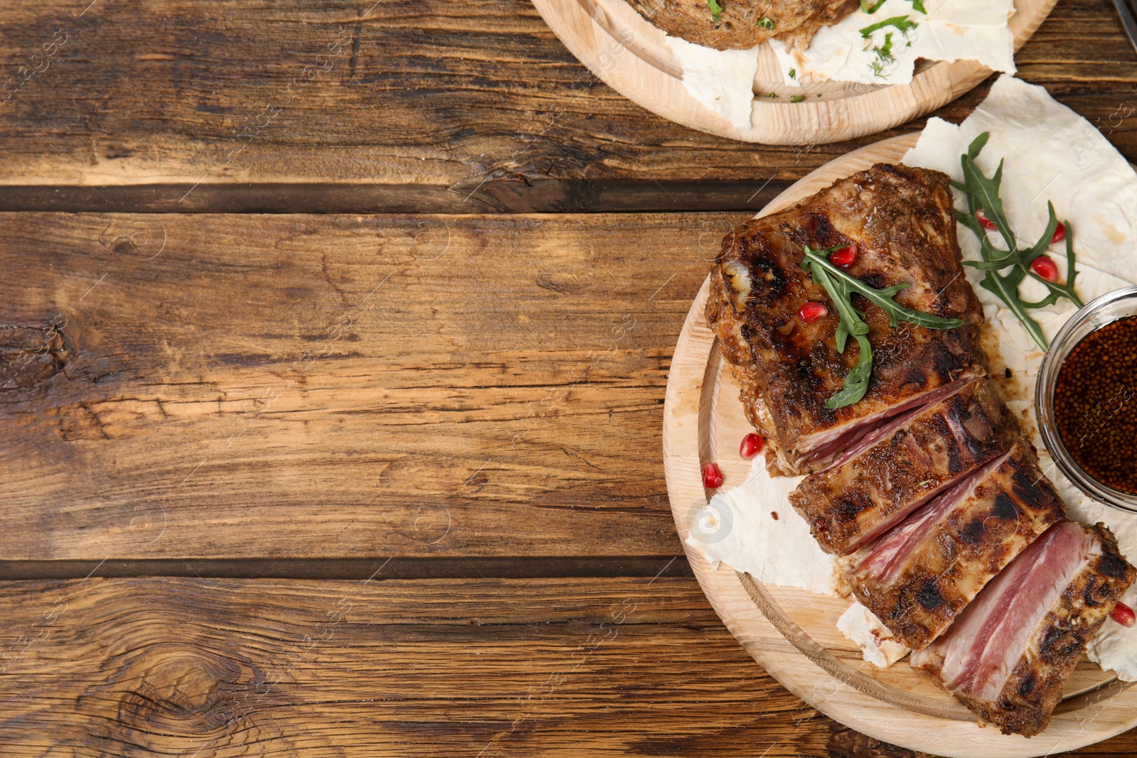 Photo of Delicious grilled ribs served on wooden table, flat lay. Space for text