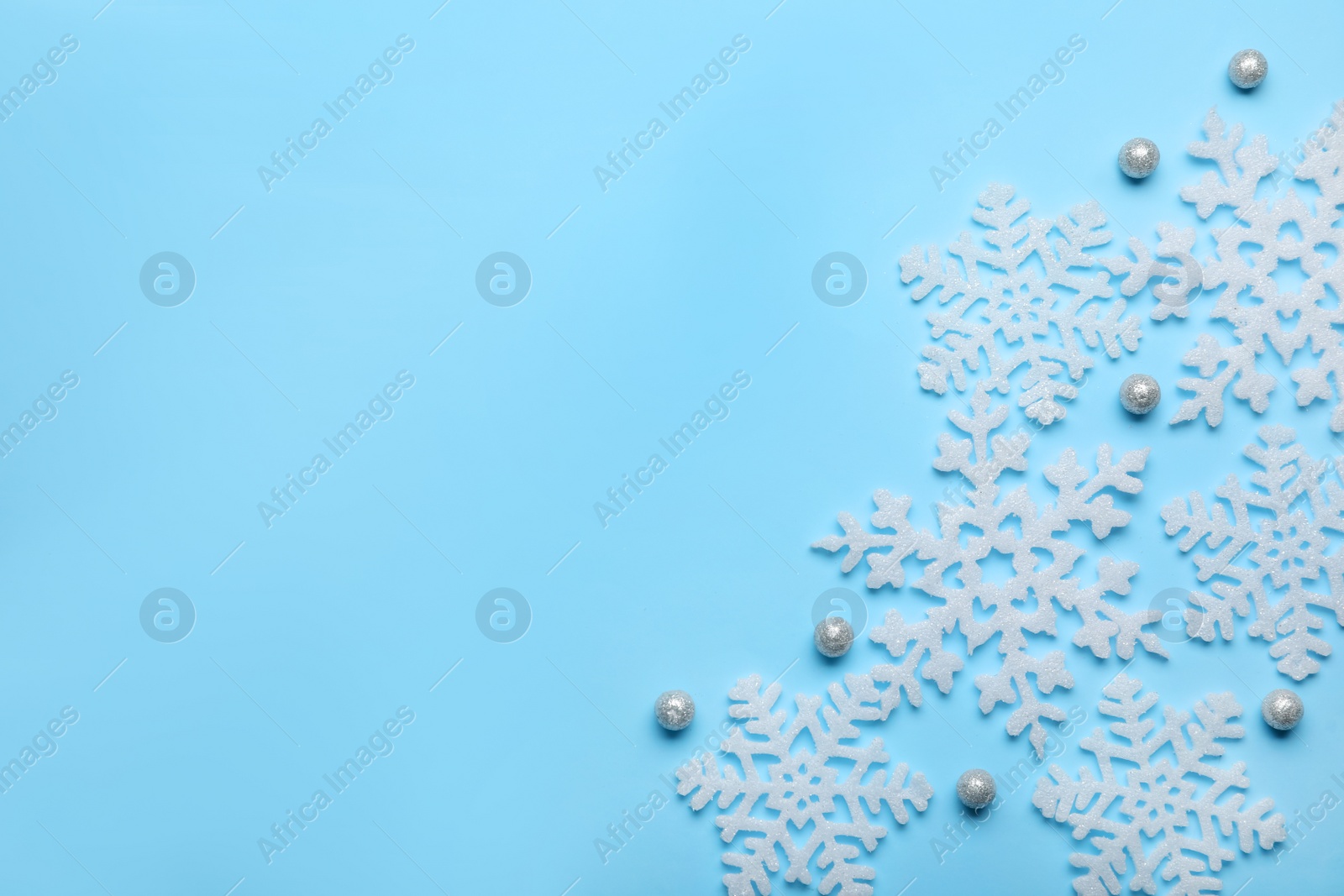 Photo of Beautiful decorative snowflakes on light blue background, flat lay. Space for text