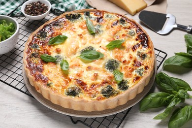 Photo of Delicious homemade quiche with salmon, broccoli and basil leaves on table