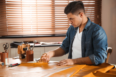 Man cutting leather with scissors in workshop