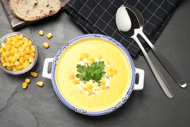 Photo of Delicious creamy corn soup served on black table, flat lay