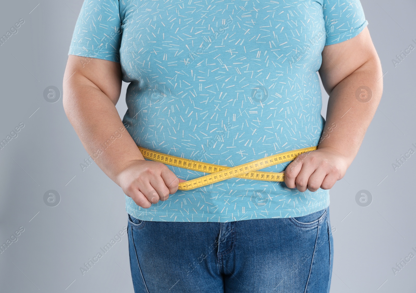 Photo of Overweight woman measuring waist before weight loss on color background