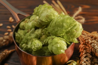 Photo of Fresh hop flowers and wheat ears on wooden table, closeup