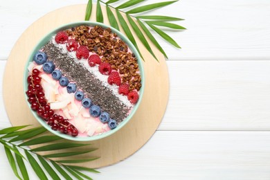 Photo of Tasty smoothie bowl with fresh berries and palm leaves on white wooden table, flat lay. Space for text