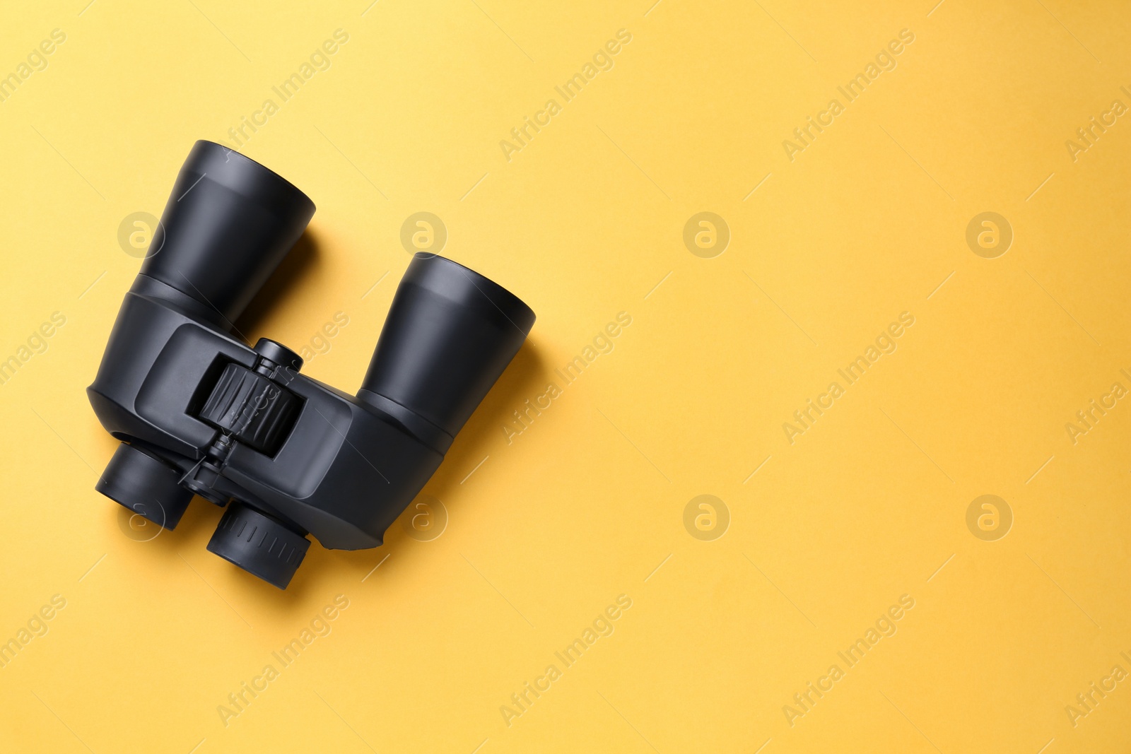 Photo of Modern binoculars on orange background, top view. Space for text