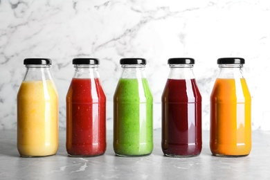 Bottles with delicious colorful juices on marble table