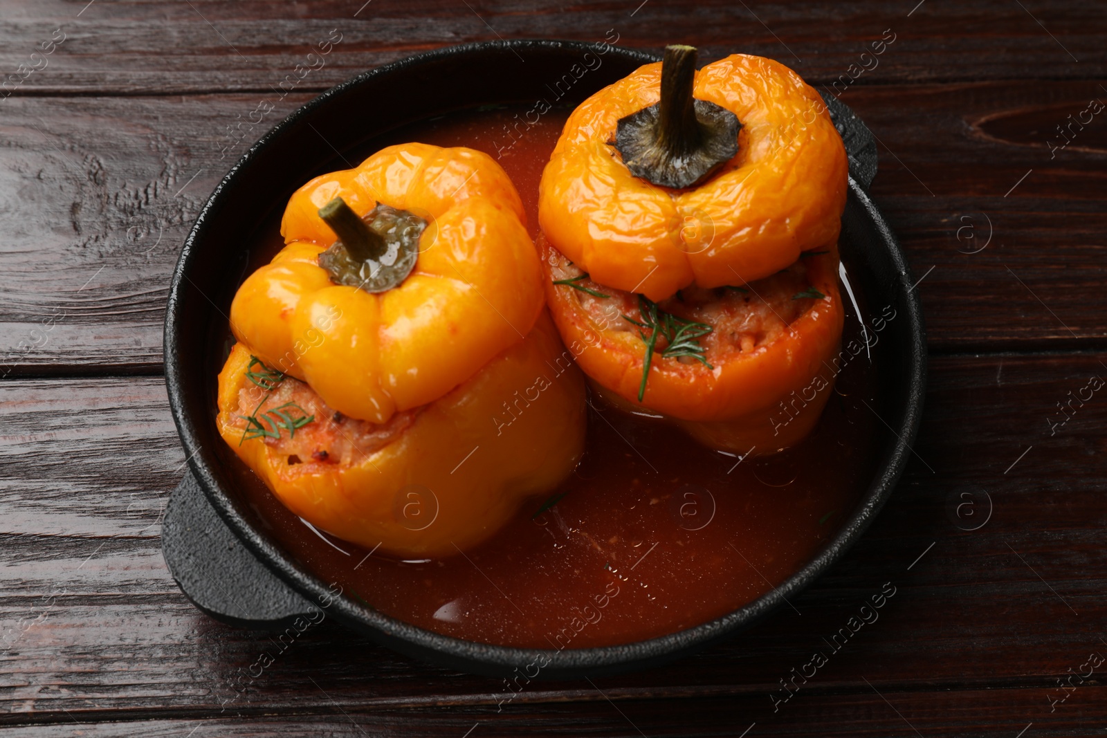 Photo of Tasty stuffed peppers in pan on wooden table, closeup