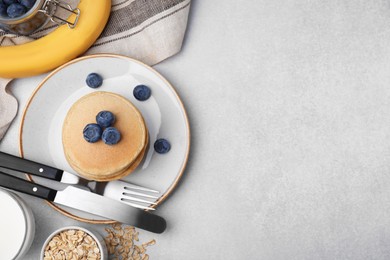 Tasty oatmeal pancakes and ingredients on grey table, flat lay. Space for text