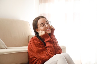 Photo of Young woman wearing knitted sweater at home