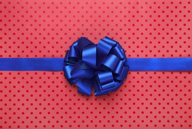 Photo of Blue ribbon with bow on red polka dot wrapping paper, top view