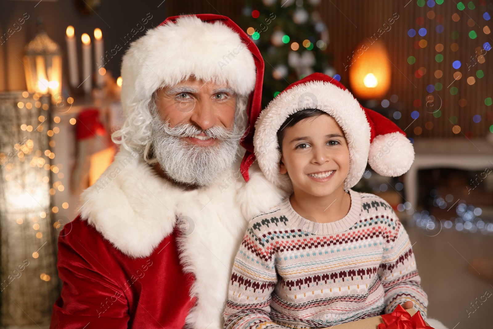 Photo of Little child with Santa Claus and Christmas gift at home