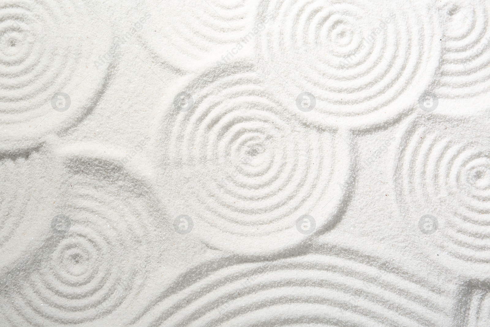 Photo of Zen rock garden. Circle patterns on white sand, top view