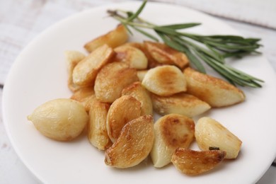 Photo of Fried garlic cloves and rosemary on plate, closeup