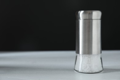 Photo of Salt shaker on white table, closeup. Space for text