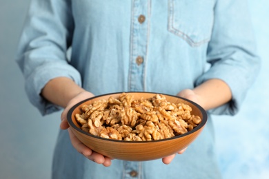 Woman holding bowl with tasty walnuts, closeup