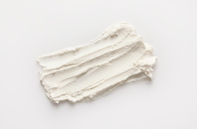 Photo of Smear of tasty cream cheese on white background, top view