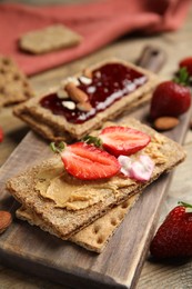 Fresh rye crispbreads with different toppings on wooden table, closeup