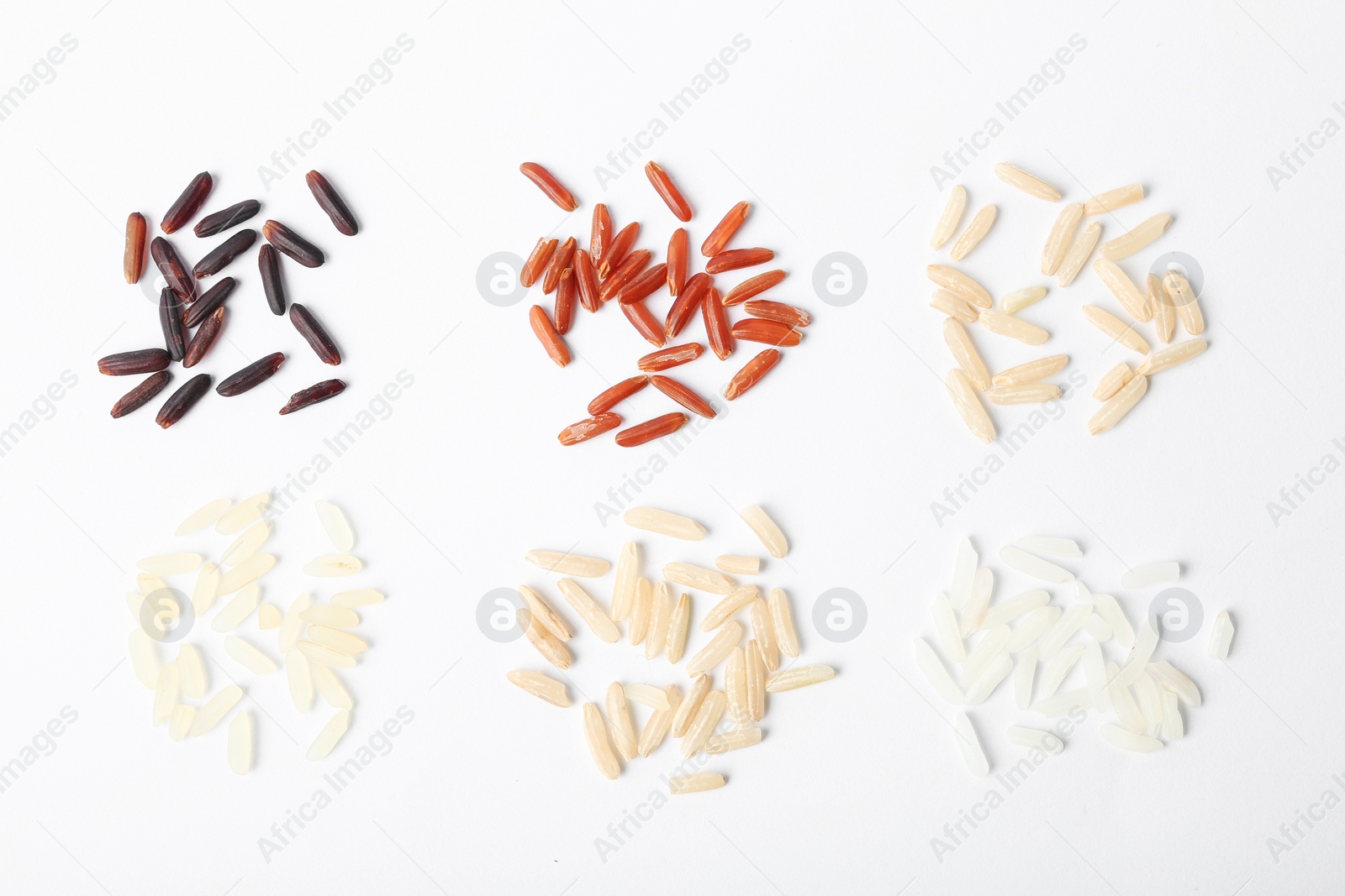 Photo of Different types of uncooked rice on white background, top view