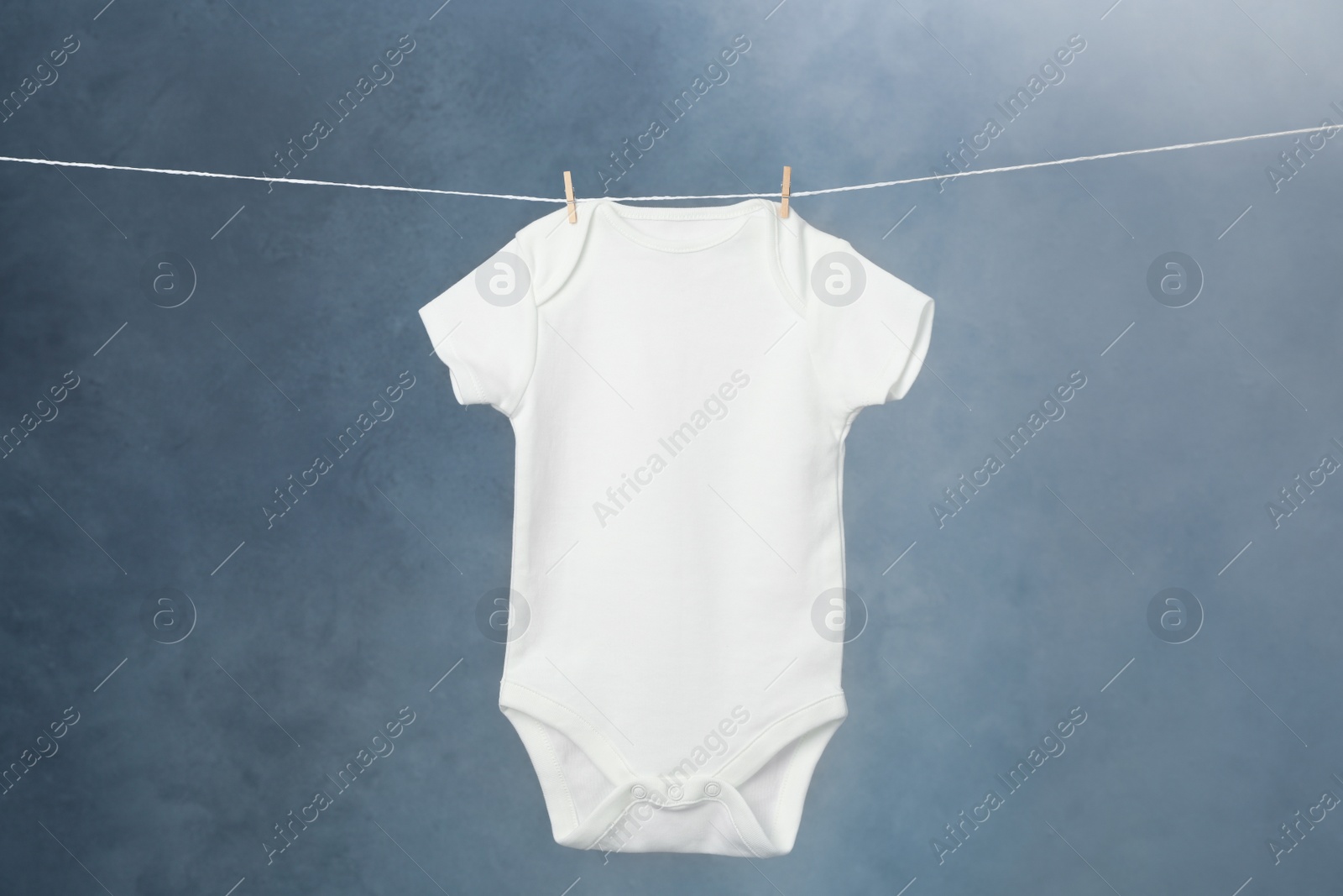 Photo of Child's bodysuit hanging on laundry line against dark background