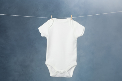 Photo of Child's bodysuit hanging on laundry line against dark background