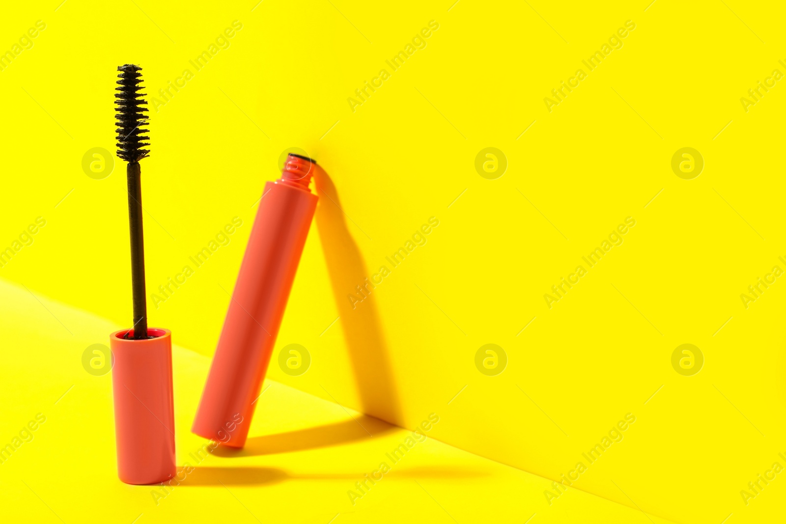 Photo of Mascara on yellow background, space for text. Makeup product