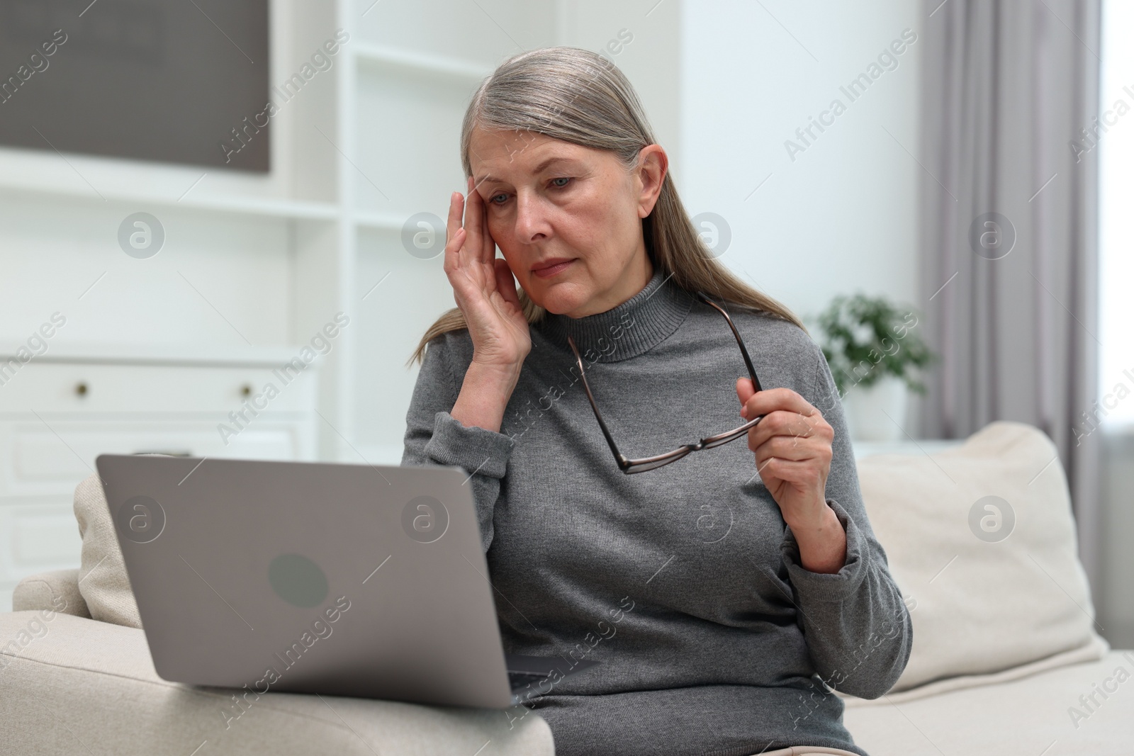 Photo of Overwhelmed woman with laptop sitting on sofa at home