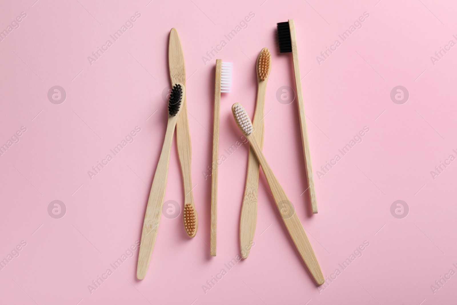 Photo of Bamboo toothbrushes on pink background, flat lay