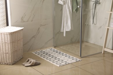 Photo of Soft bath mat and slippers on floor in bathroom