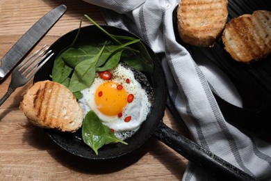 Photo of Delicious fried egg with spinach and chilli served on wooden table, flat lay
