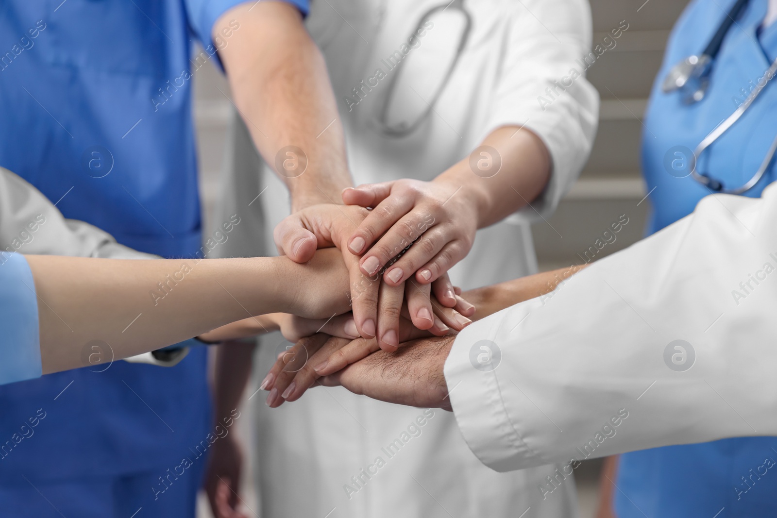 Photo of Team of medical doctors putting hands together indoors, closeup