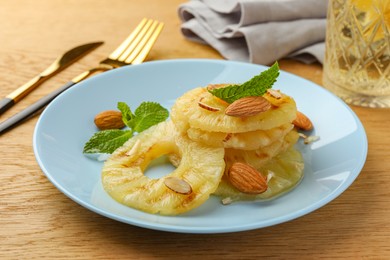 Tasty grilled pineapple slices, almonds and mint on wooden table