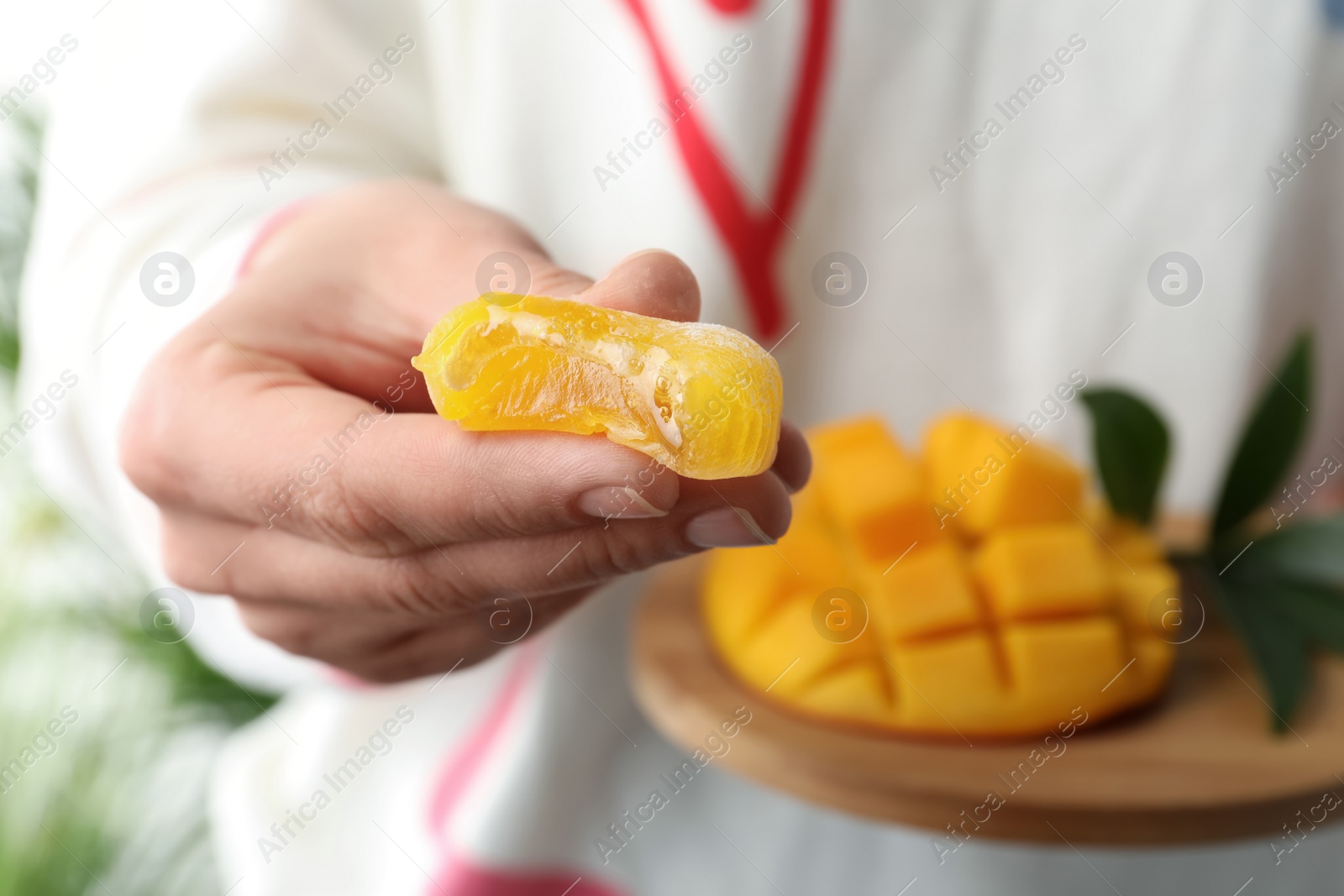 Photo of Woman holding delicious mango mochi, closeup. Japanese cuisine