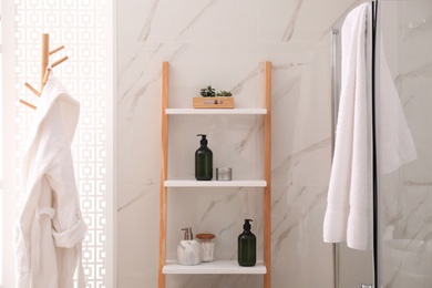 Photo of Plants and different toiletries on decorative ladder in bathroom. Interior design