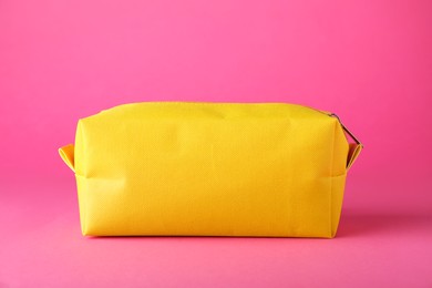 Photo of Stylish yellow cosmetic bag on pink background