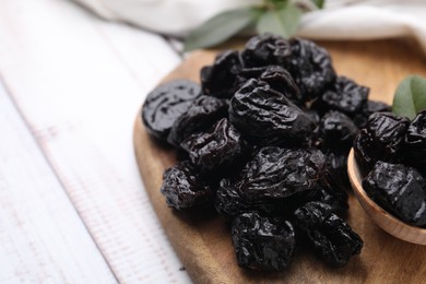 Photo of Tasty dried prunes on light wooden table, closeup. Space for text