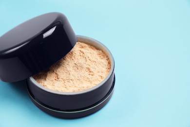 Photo of One face powder on light blue background, closeup. Space for text