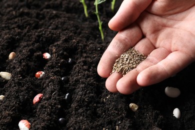 Photo of Woman planting carrot seeds into fertile soil, closeup. Vegetable growing