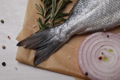 Photo of Raw dorado fish, spices and onion on white wooden table, flat lay