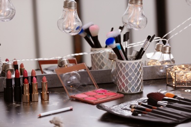 Photo of Decorative cosmetics and tools on dressing table in makeup room
