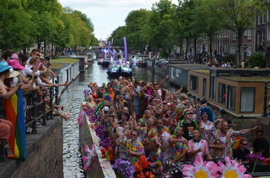 AMSTERDAM, NETHERLANDS - AUGUST 06, 2022: Many people in boats at LGBT pride parade on river